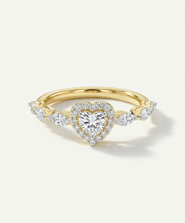 Gold ring with a heart-shaped diamond on a light beige background