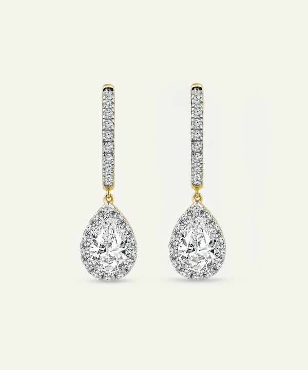 Pair of teardrop-shaped diamond earrings on a light beige background