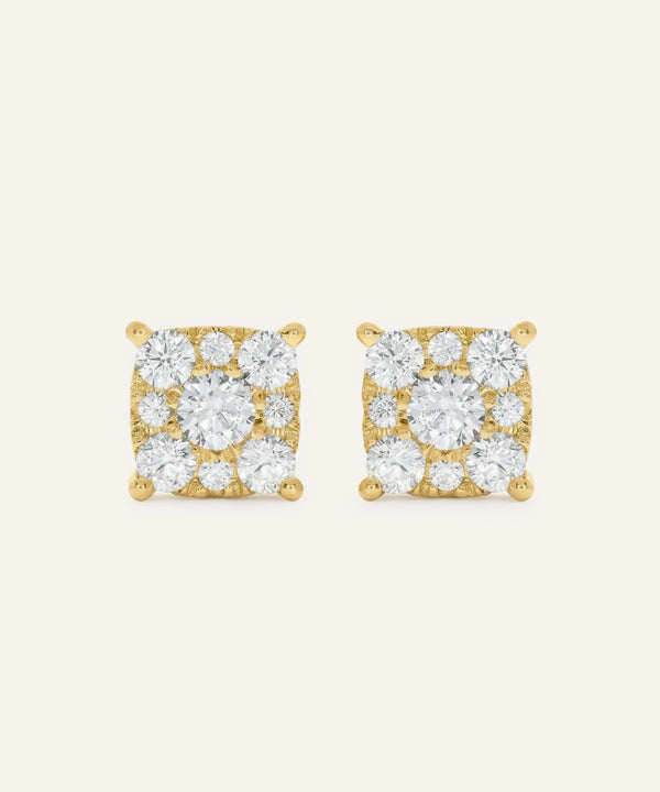 Pair of gold square-shaped earrings with clear gemstones on a beige background