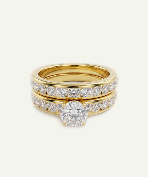 A gold ring set featuring a solitaire diamond engagement ring and two matching diamond bands, displayed on a clean off-white background.