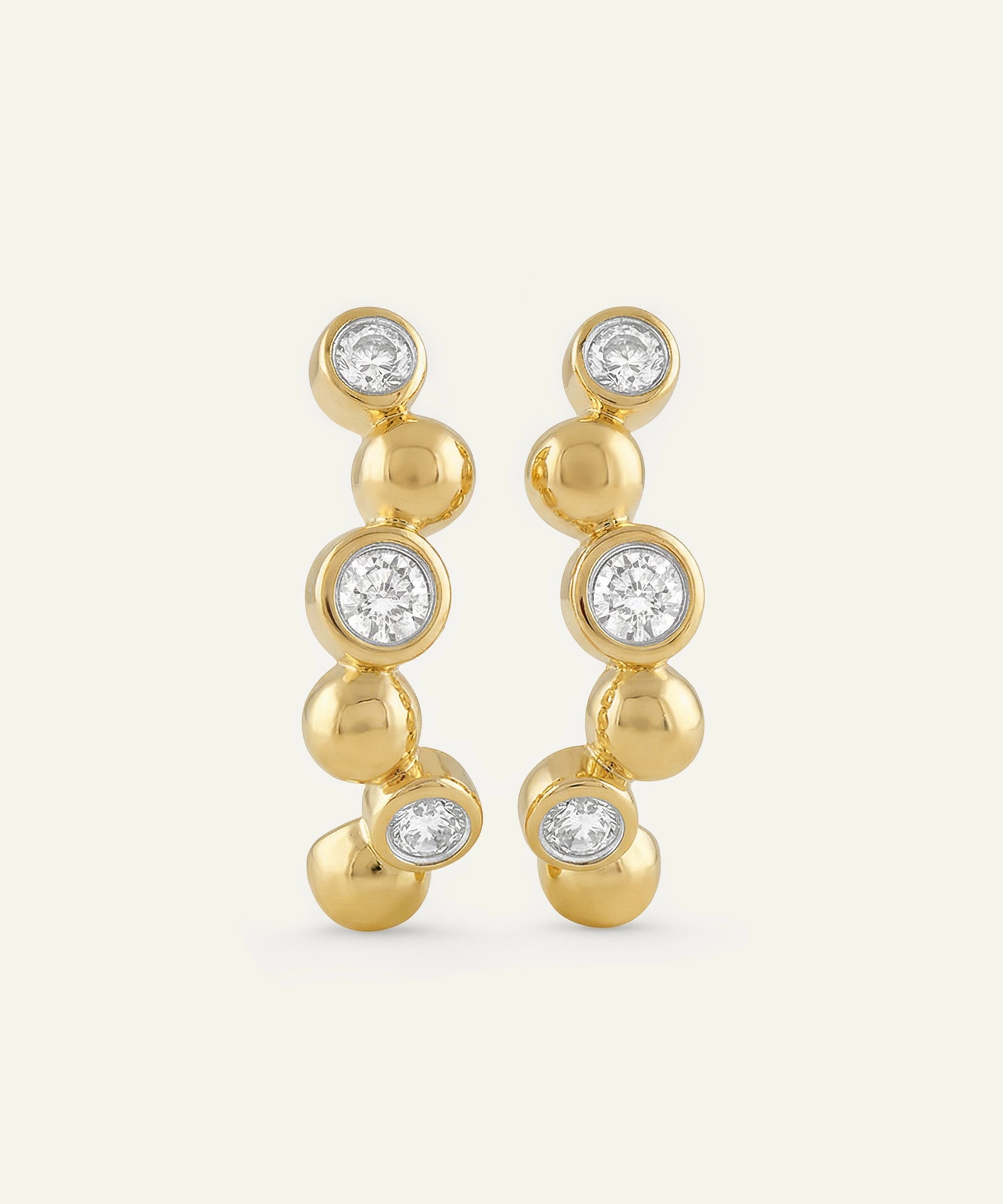 Gold earrings with clear gemstones on a white background