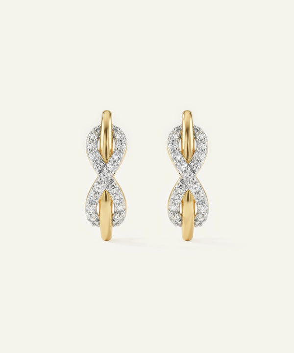 Gold and diamond earrings on a light beige background