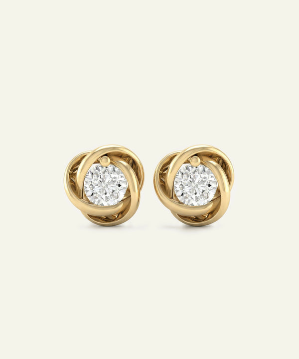 Gold earrings with diamond-like centers on a light beige background