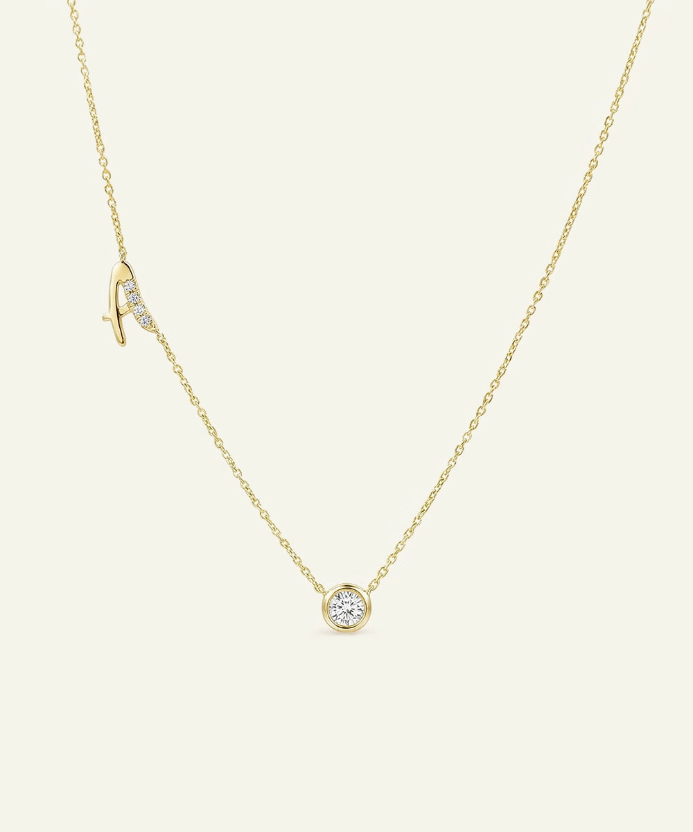 Gold necklace with a small round pendant on a light beige background