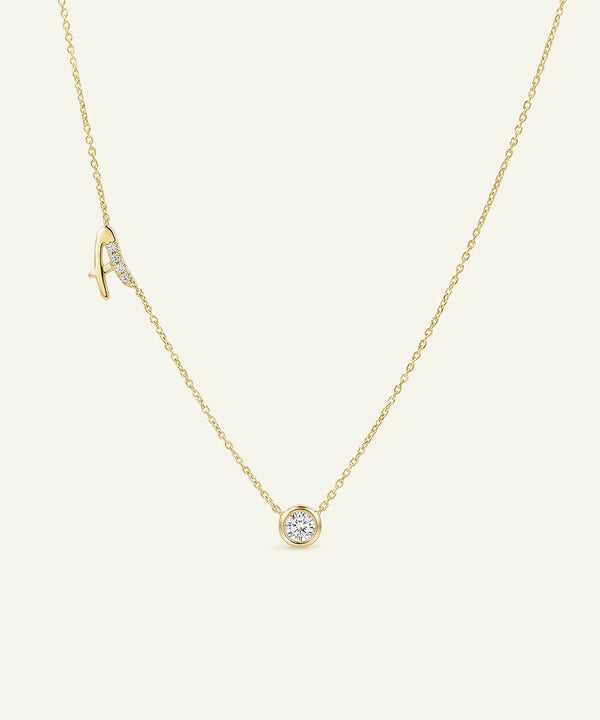 Gold necklace with a small round pendant on a light beige background