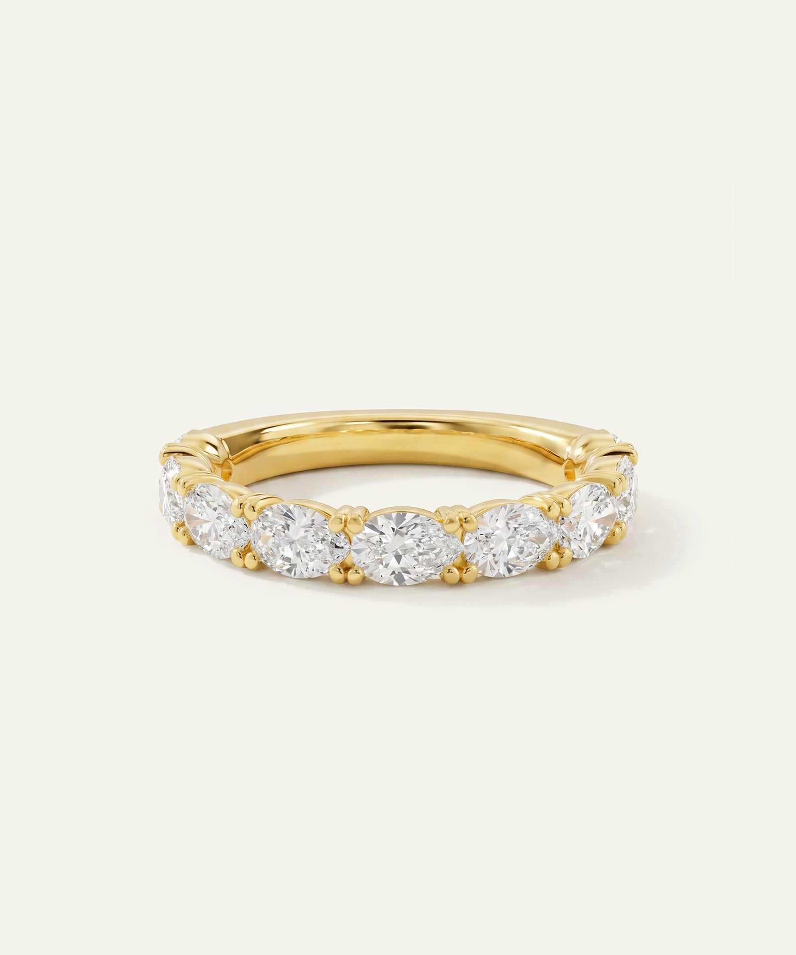 A yellow gold eternity ring featuring a row of round-cut clear gemstones, photographed on a clean, light off-white background.