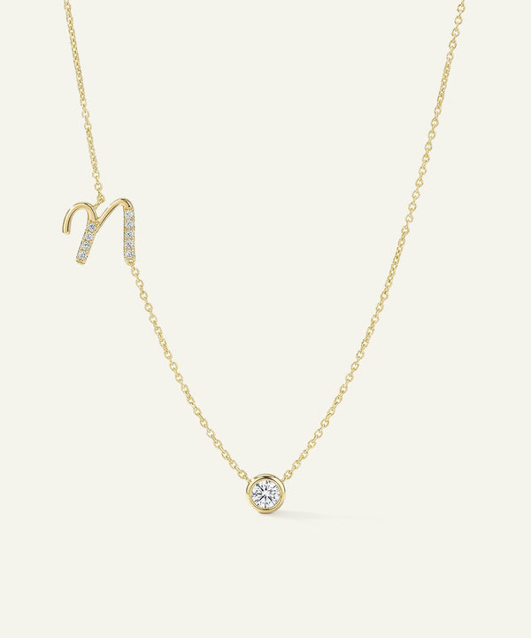 Gold necklace with a zodiac sign pendant on a light beige background