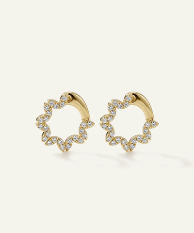 Gold hoop earrings with diamond accents on a light beige background