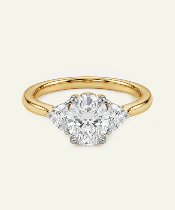 Oval diamond three-stone engagement ring with a yellow gold band