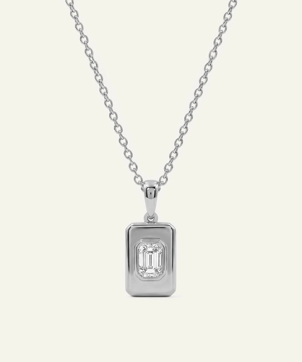 Silver necklace with a rectangular diamond pendant on a light gray background