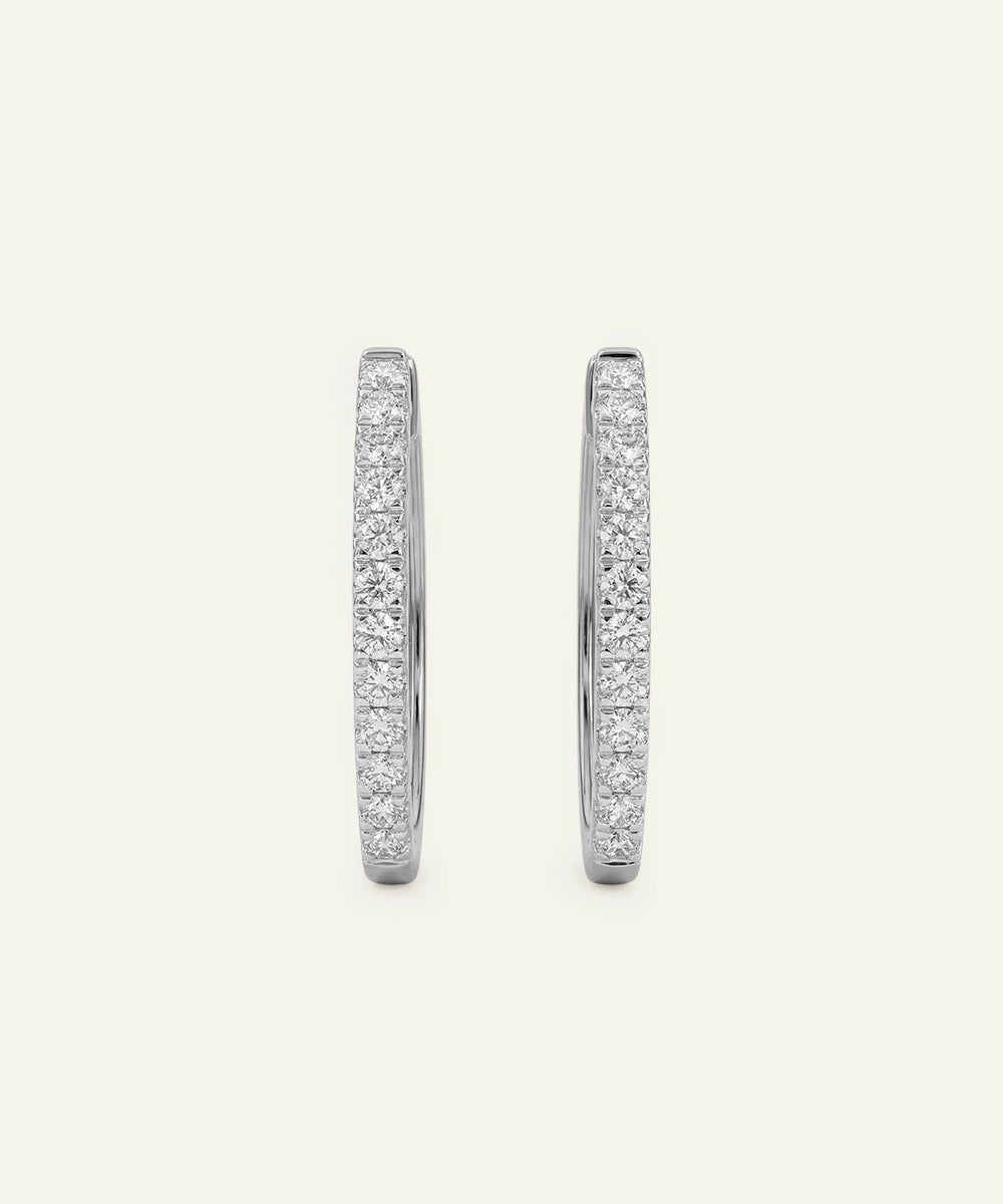 Pair of silver hoop earrings with embedded stones on a light gray background