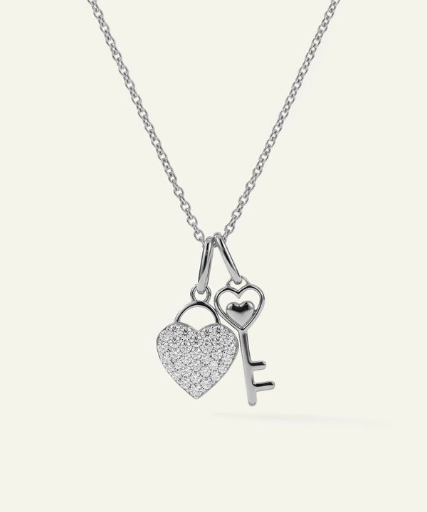 Silver necklace with heart and key pendants on a white background