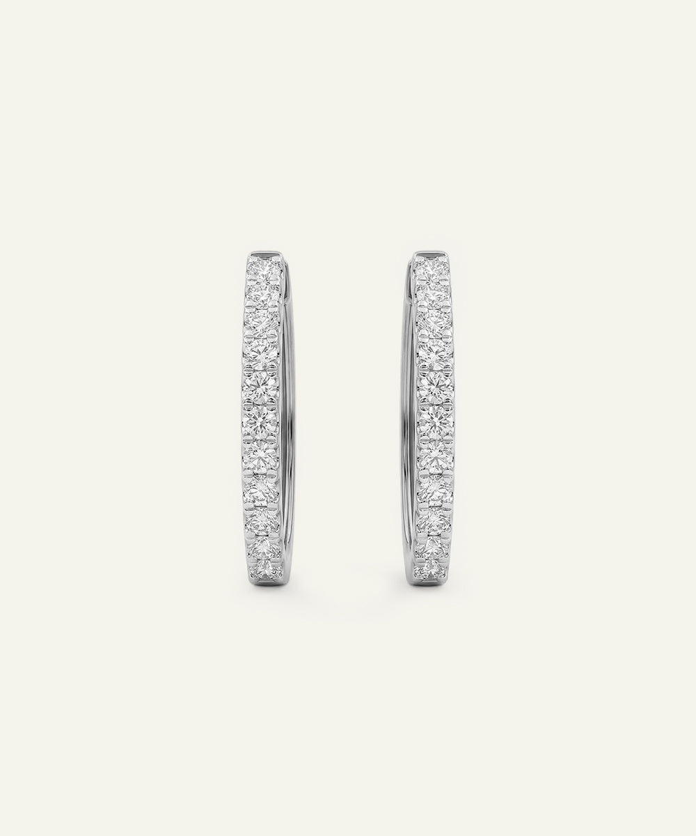 Pair of silver hoop earrings with embedded stones on a light gray background