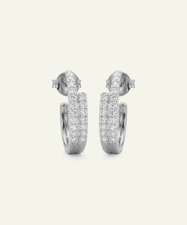 Pair of silver hoop earrings with clear gemstones on a light gray background