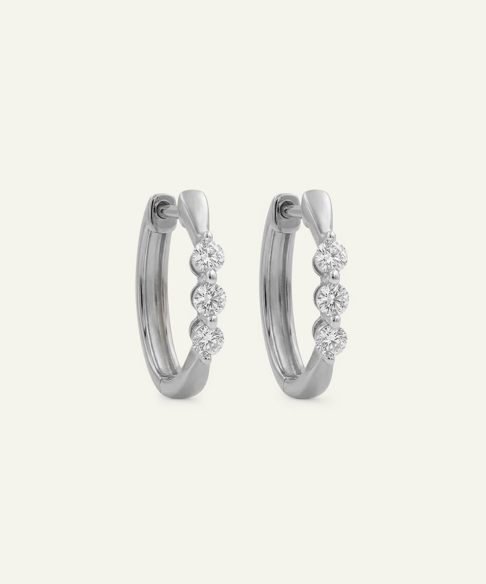 Pair of silver hoop earrings with small diamonds on a light gray background
