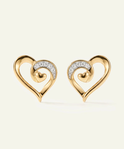 Gold heart-shaped earrings with diamond accents on a light beige background