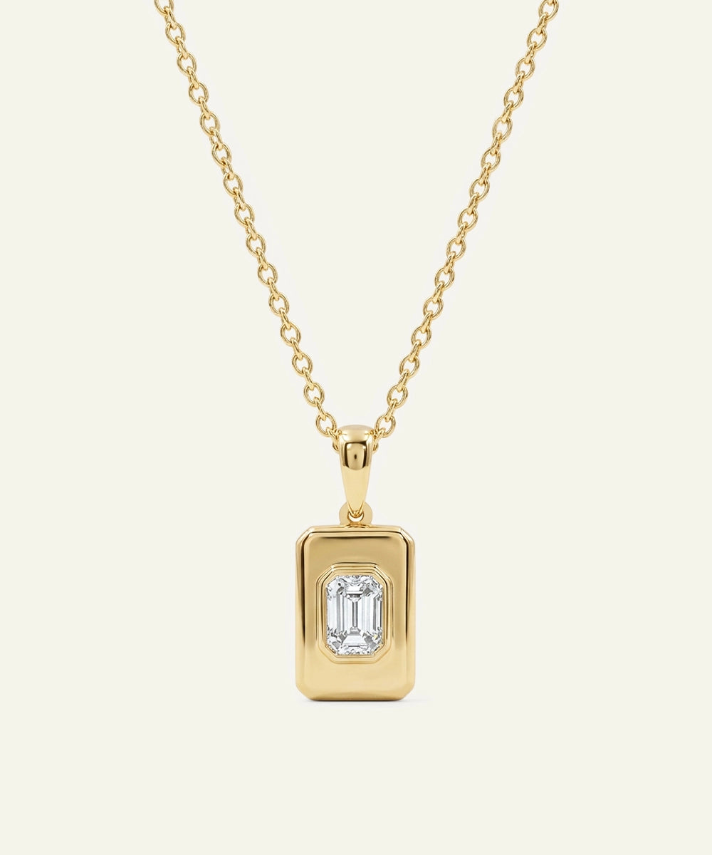 Gold necklace with a rectangular pendant on a beige background
