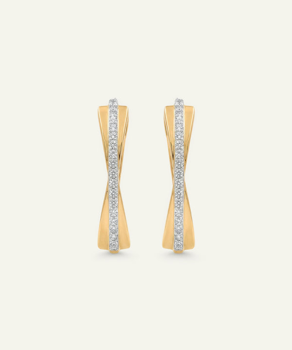 Gold earrings with diamond accents on a light beige background
