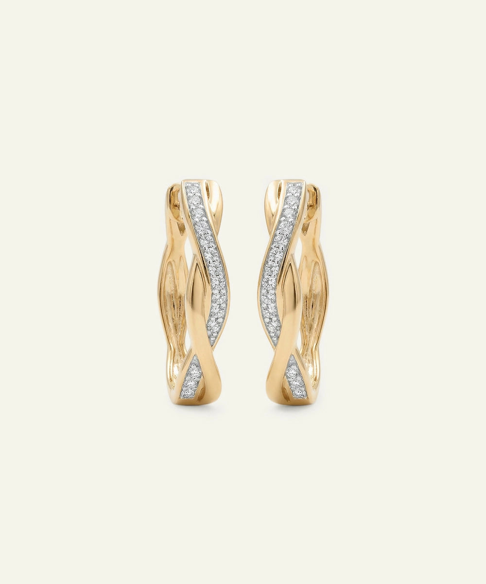 Gold hoop earrings with diamond accents on a light beige background