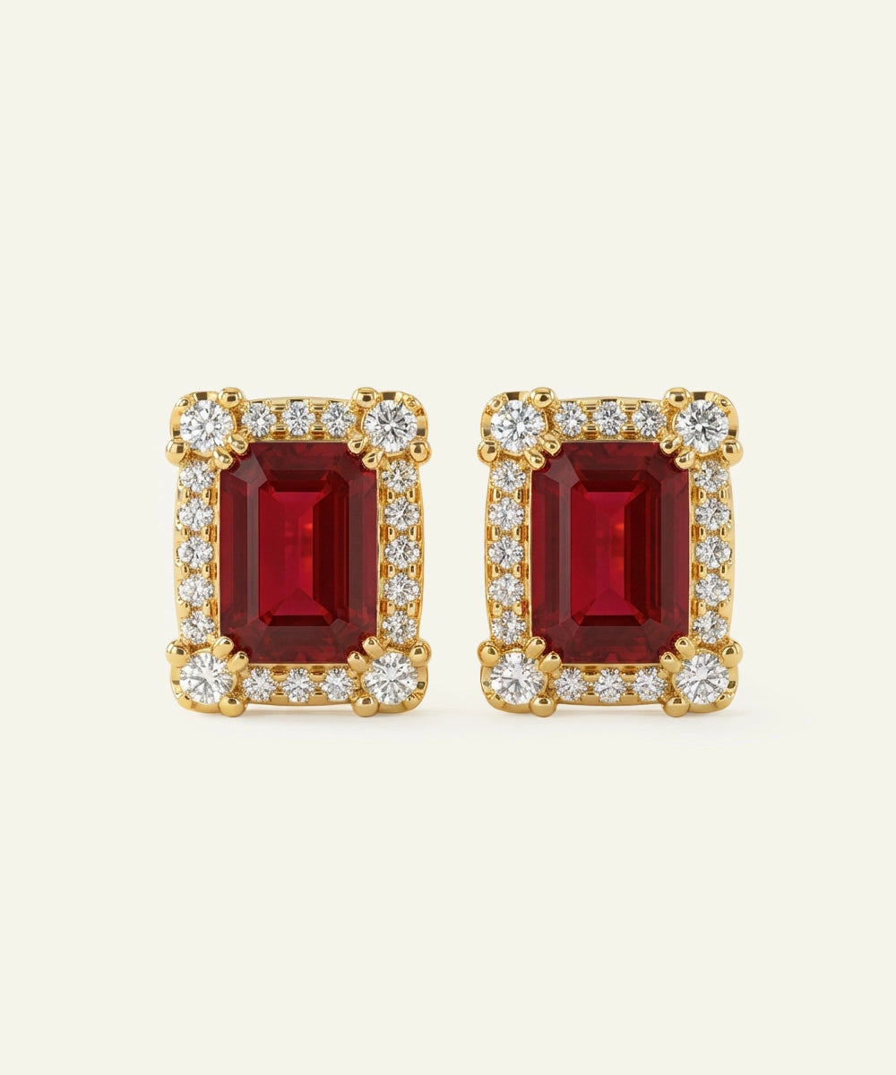 Pair of gold earrings with red gemstones on a white background