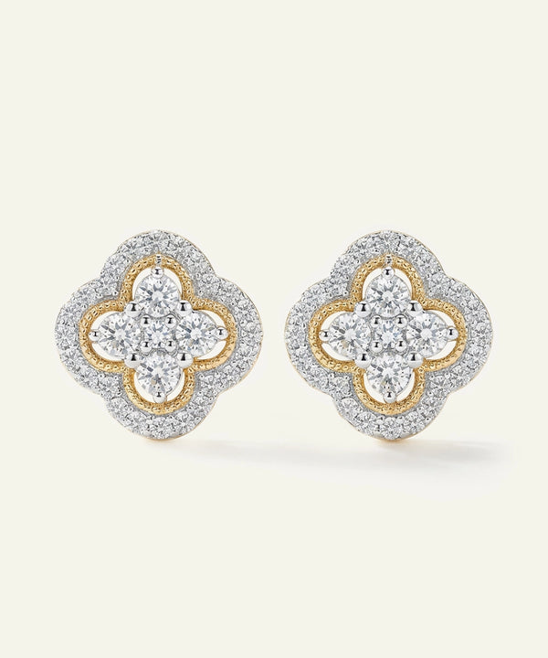 Pair of diamond earrings with gold and silver design on a light beige background