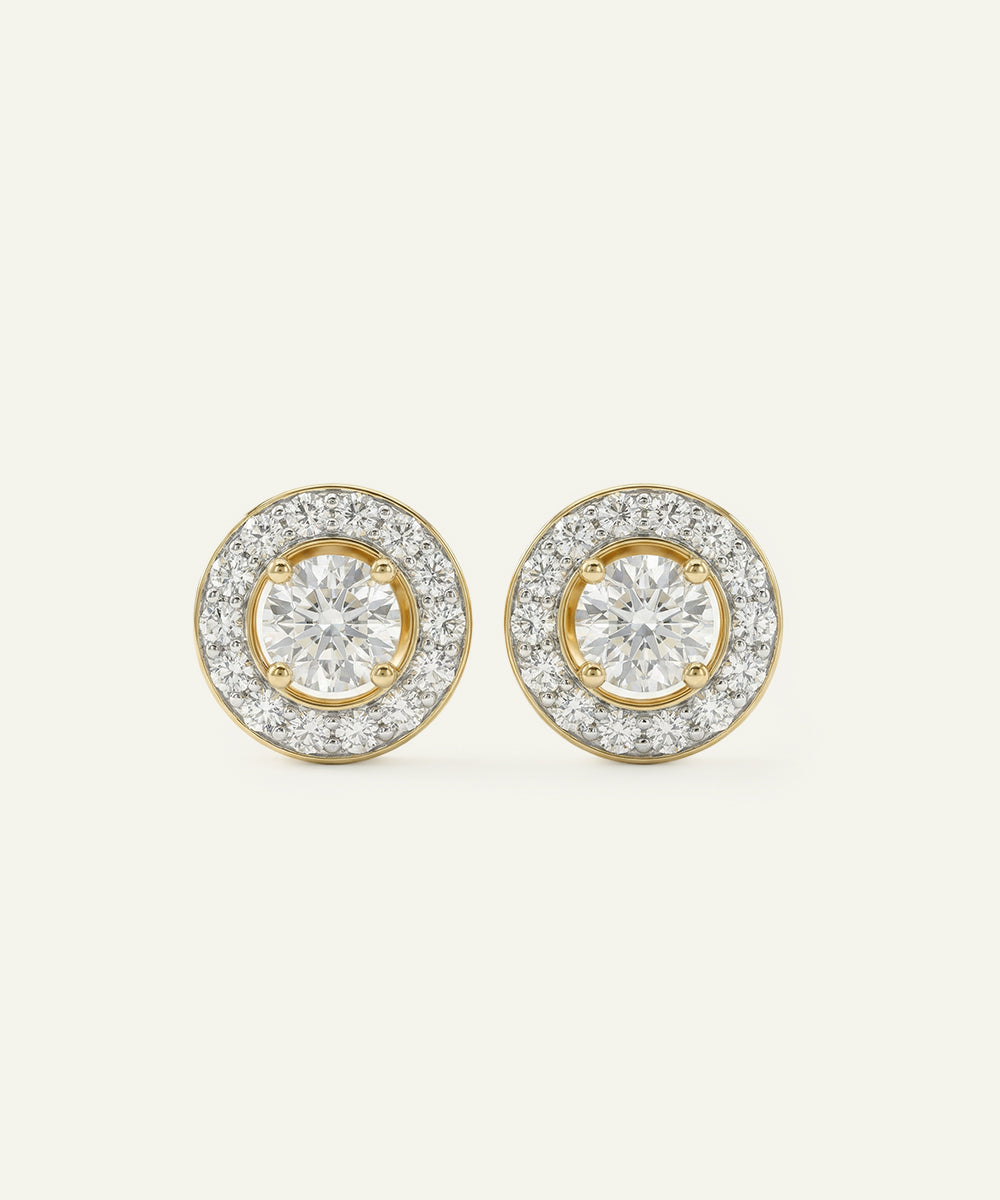 Pair of gold and diamond earrings on a light beige background