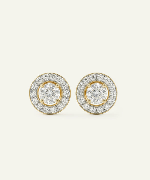 Pair of gold and diamond earrings on a light beige background