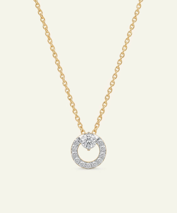 Gold necklace with a diamond pendant on a light beige background