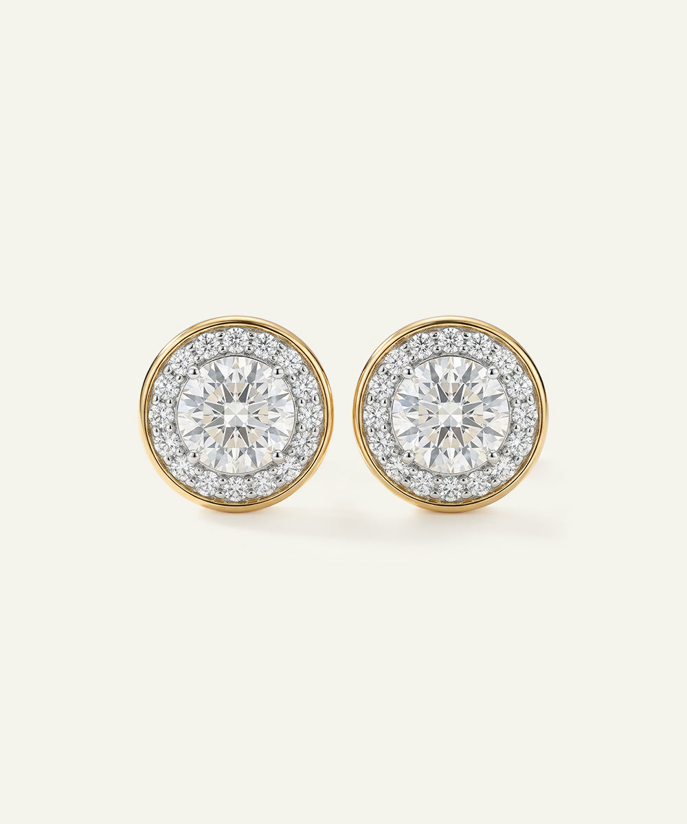 Pair of diamond earrings with gold rims on a light gray background