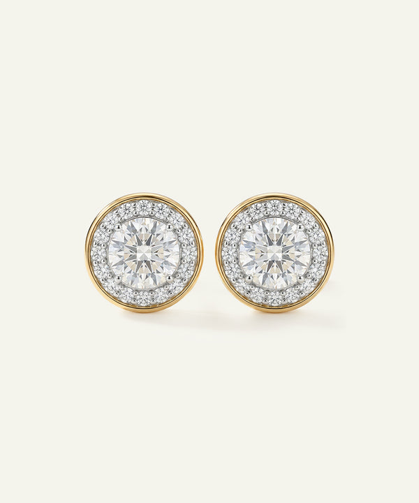 Pair of diamond earrings with gold rims on a light gray background
