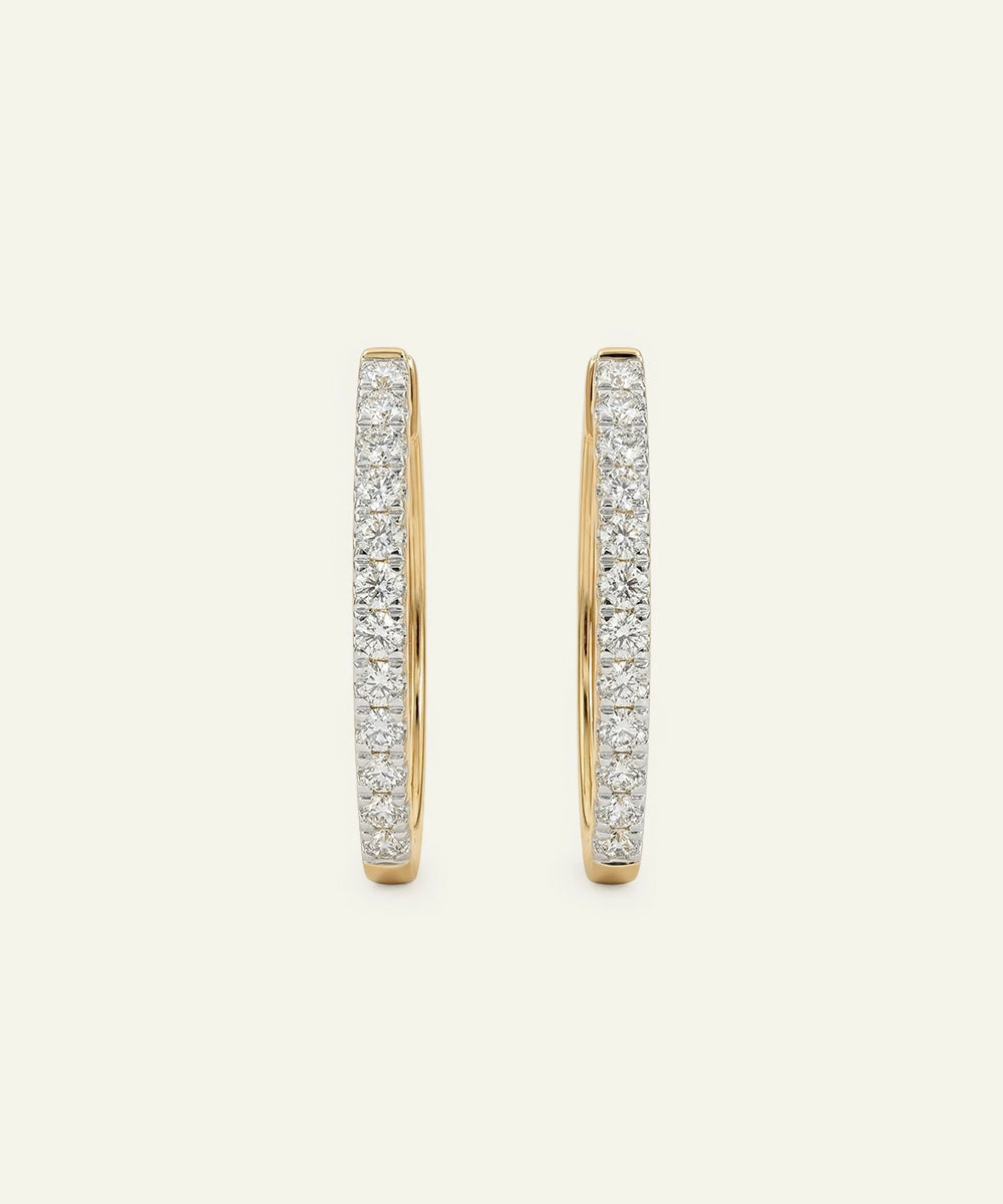 Gold hoop earrings with diamond accents on a light beige background