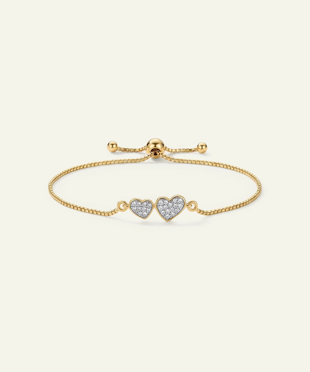 Gold bracelet with heart-shaped charms on a light beige background