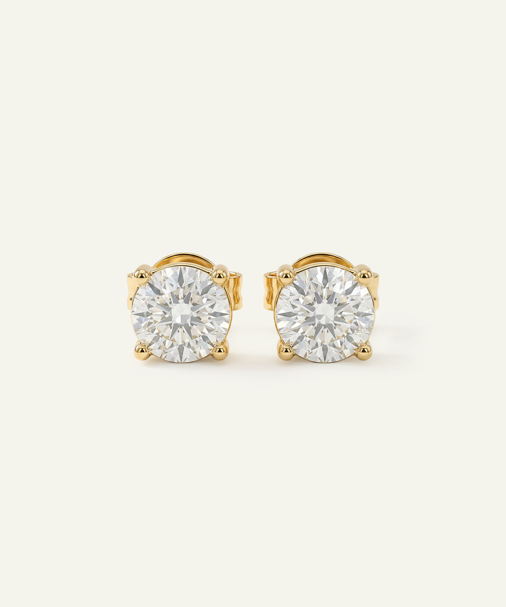 Pair of gold stud earrings with clear gemstones on a white background