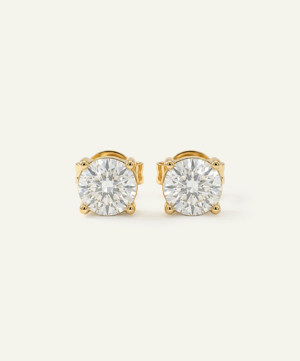 Pair of gold stud earrings with clear gemstones on a white background