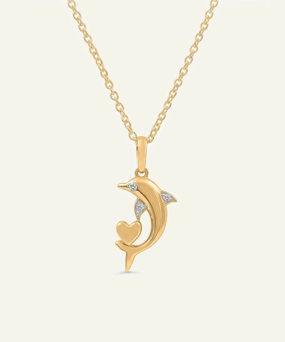 Gold necklace with a dolphin pendant on a light beige background