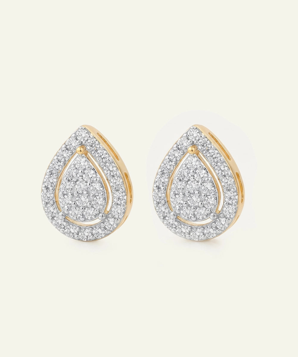 Teardrop-shaped earrings with gold and diamond accents on a light beige background