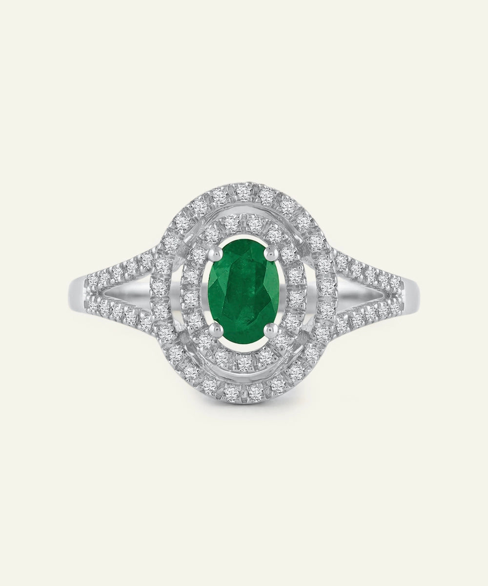 Ring with a green gemstone and diamond-studded band on a white background