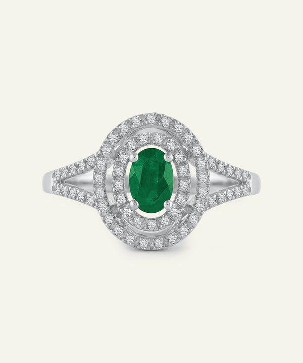 Ring with a green gemstone and diamond-studded band on a white background