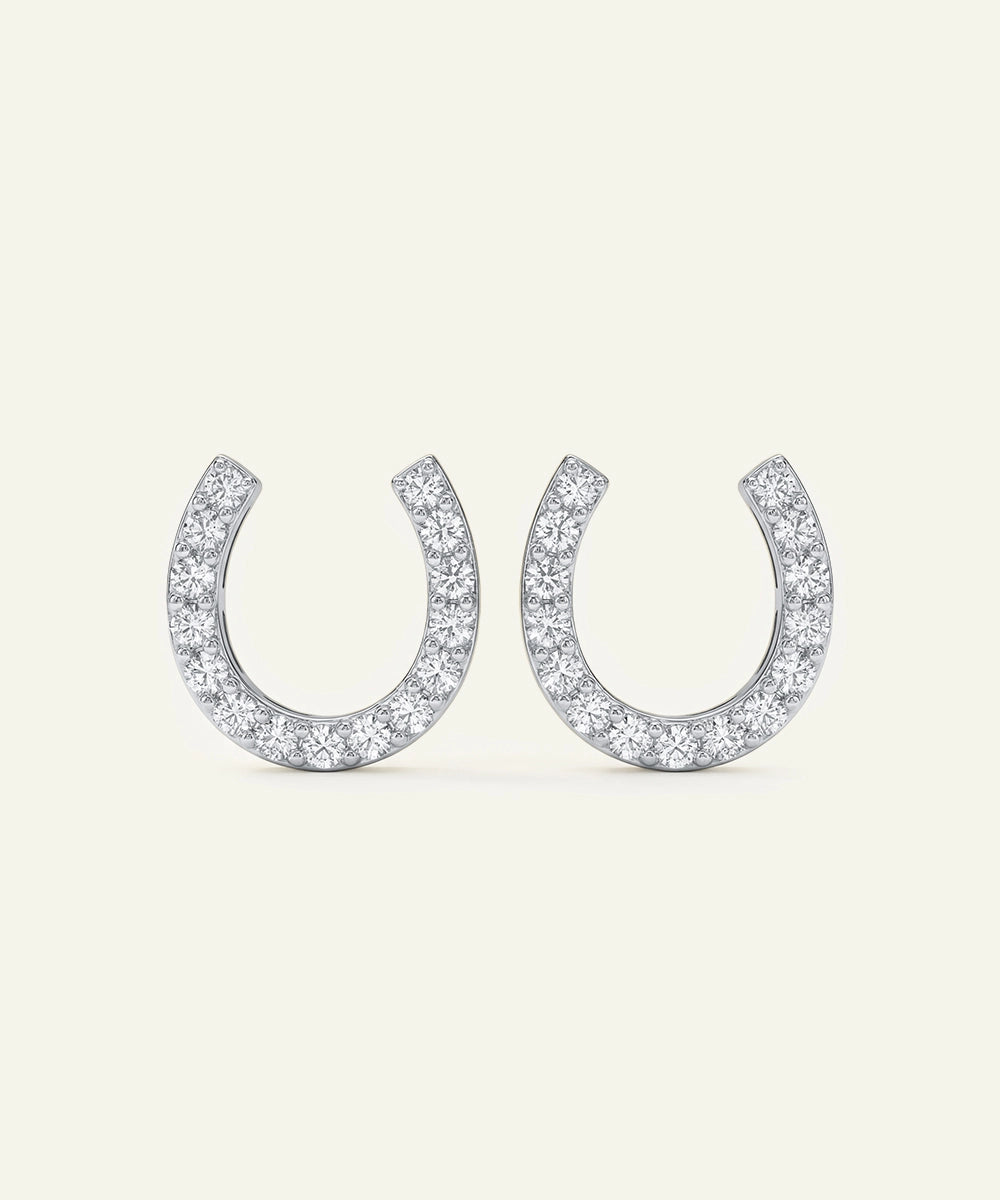 Pair of silver horseshoe-shaped earrings with clear gemstones on a white background