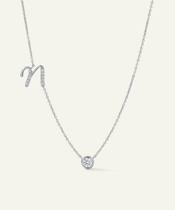 Silver necklace with a small round pendant on a light gray background