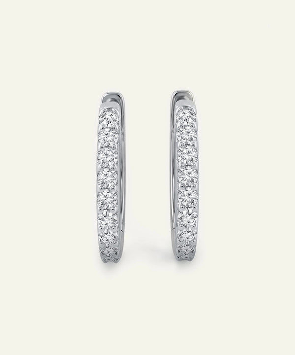 Pair of silver hoop earrings with embedded stones on a light gray background