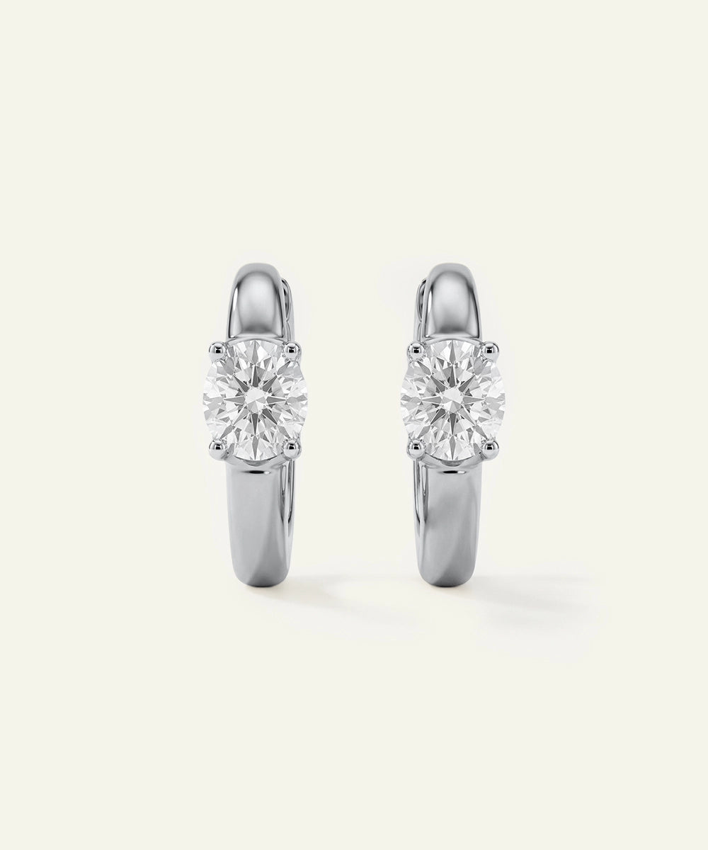 Pair of silver hoop earrings with clear gemstones on a white background