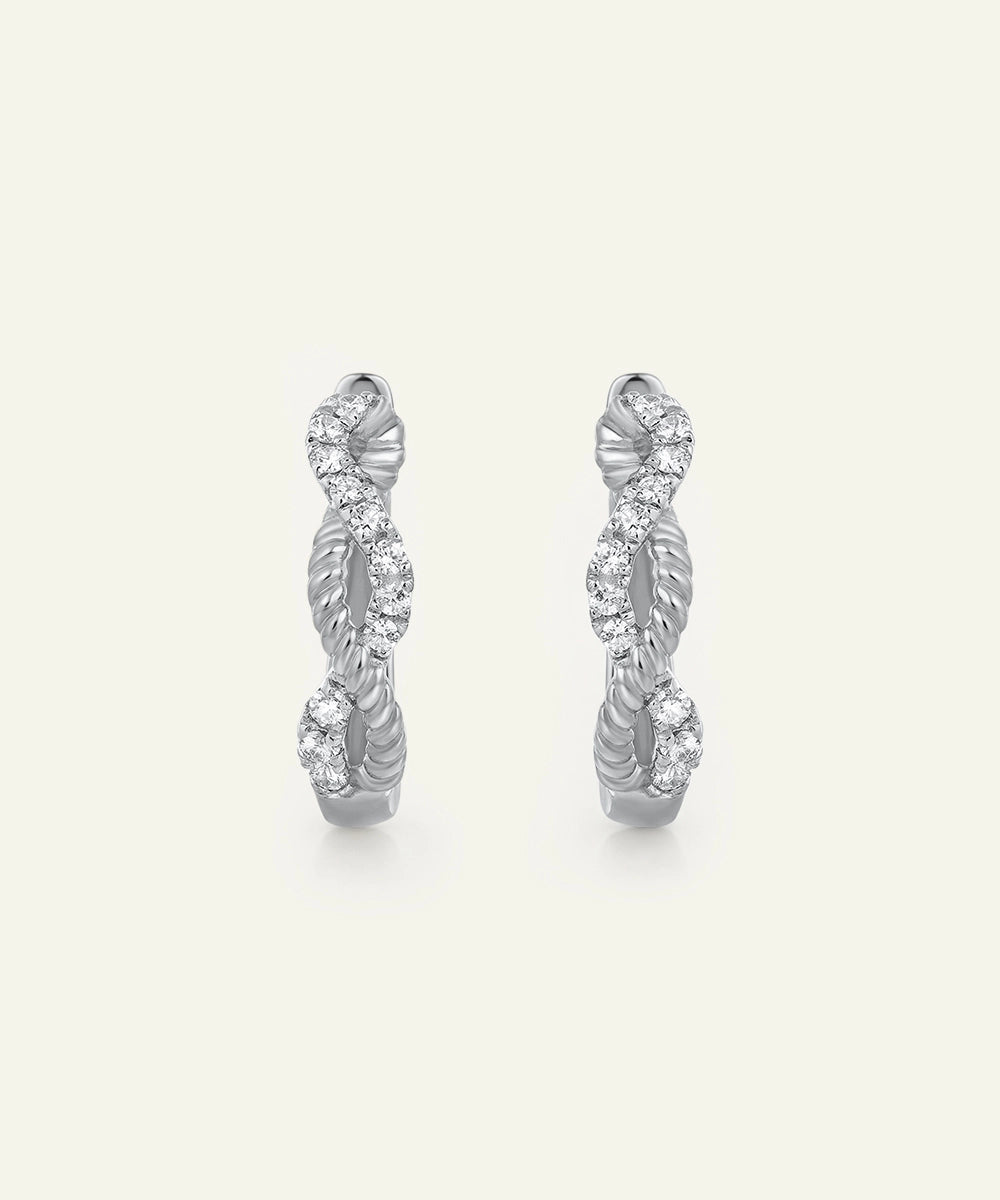 Pair of silver hoop earrings with diamond accents on a light gray background