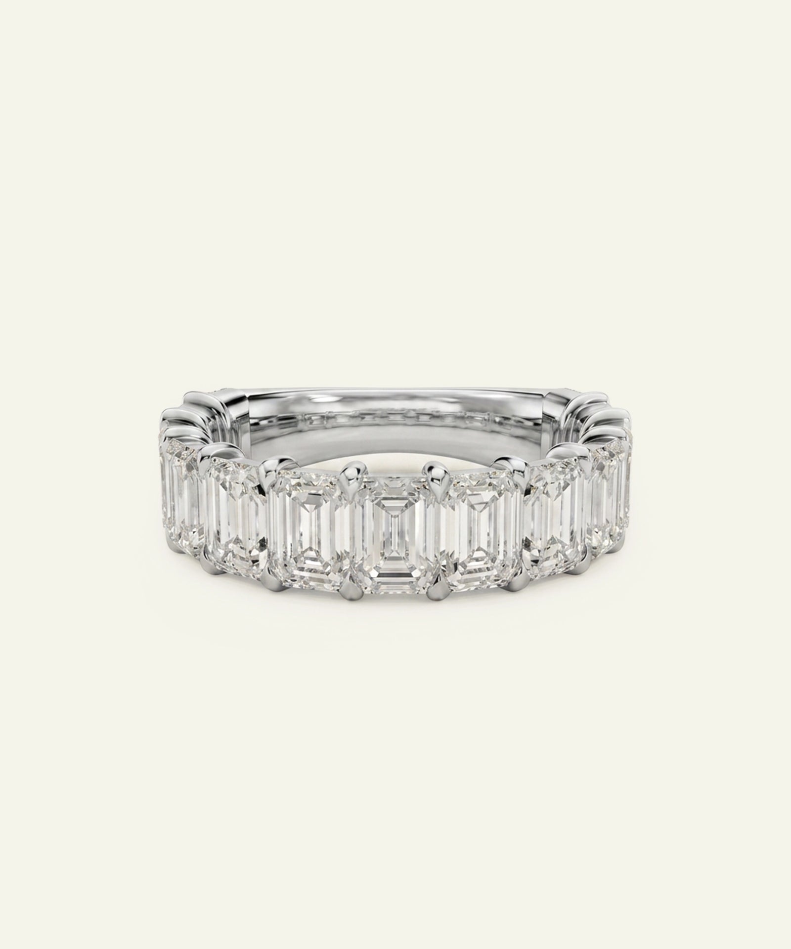 A silver-toned eternity ring featuring a row of baguette-cut clear gemstones, photographed against a solid off-white background.