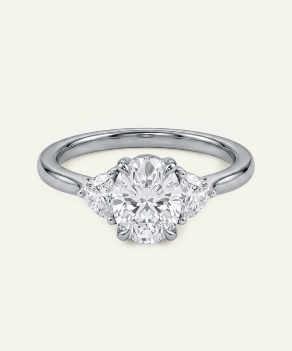 Oval diamond three-stone engagement ring with half-moon accent diamonds.