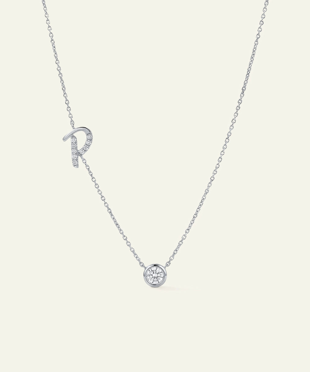 Silver necklace with 'R' pendant on a light gray background