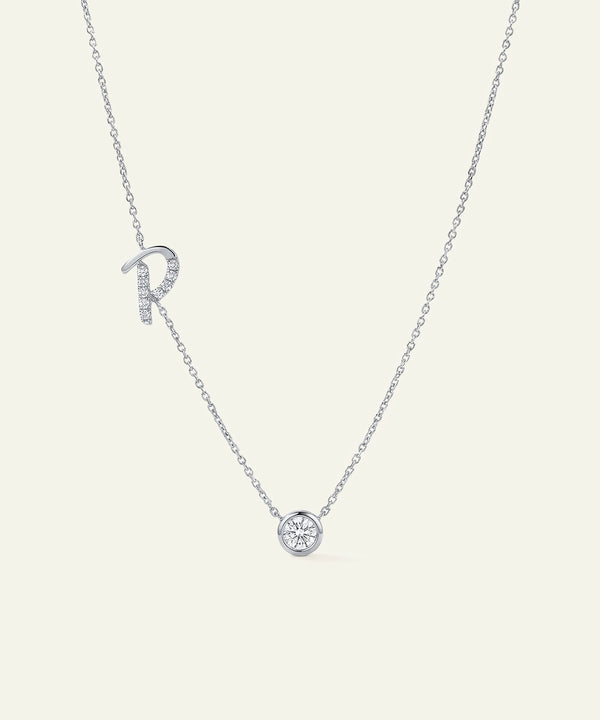 Silver necklace with 'R' pendant on a light gray background