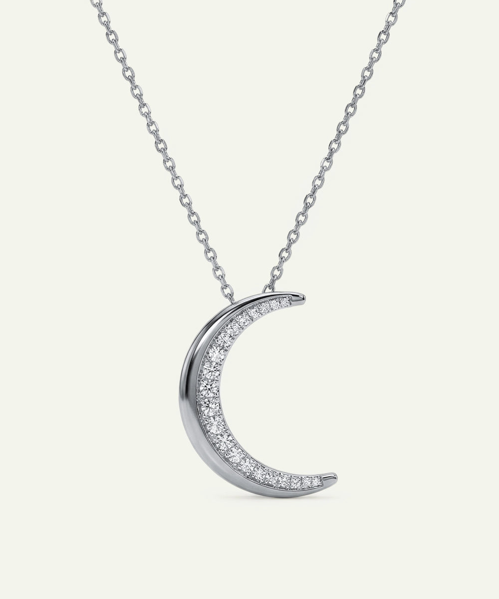 Silver crescent moon necklace with small diamonds on a white background