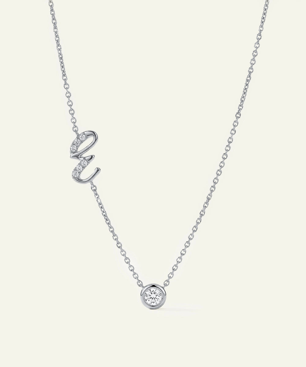 Silver necklace with a heart and round pendant on a light gray background