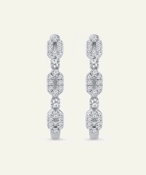 Pair of diamond earrings on a light beige background